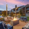 a patio with a fire pit and chairs and a building with a sunset